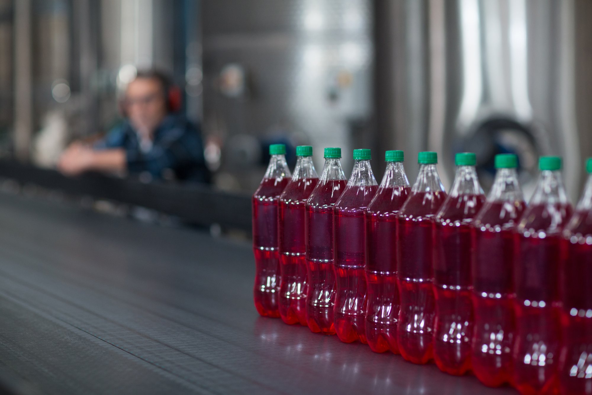 bottles-of-juice-on-conveyer-belt-2023-11-27-05-10-39-utc